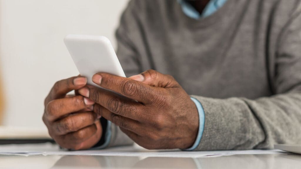 A senior man using smartphone while sitting at a table. Senior using messaging apps for communication